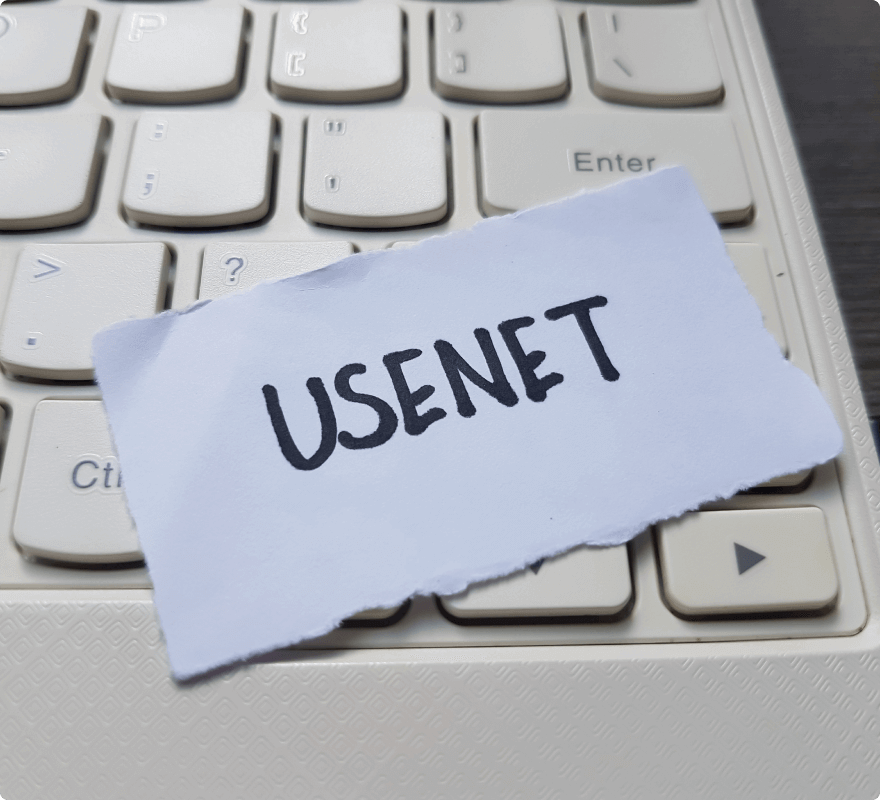The word ‘Usenet’ written on a piece of paper on a computer keyboard, symbolizing the ‘news’ Usenet newsgroup for discussing the latest news.