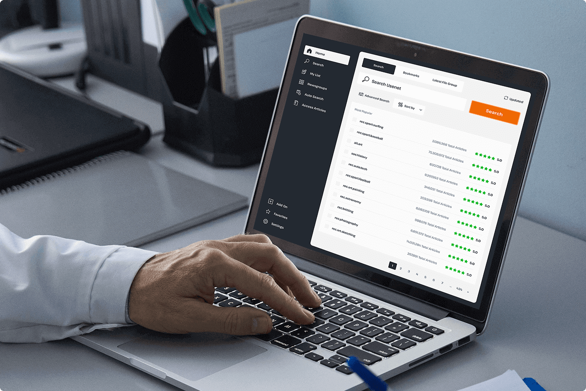 A person types on an open laptop that is open to a Usenet search page showing different Usenet newsgroups.