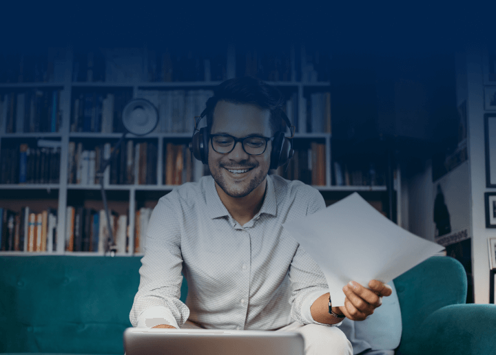 A man sits on a couch wearing headphones while using a laptop, representing the ease with which users can complete DNS troubleshooting with UsenetServer. 
