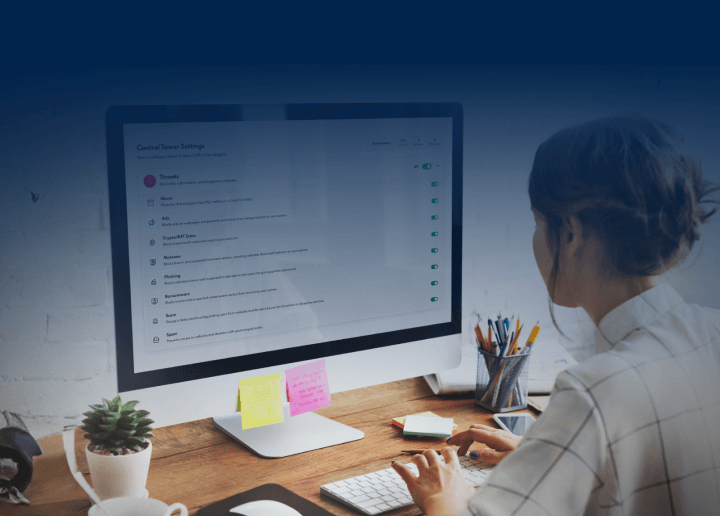 A woman sits at a desktop computer, setting up UsenetServer’s threat protection.