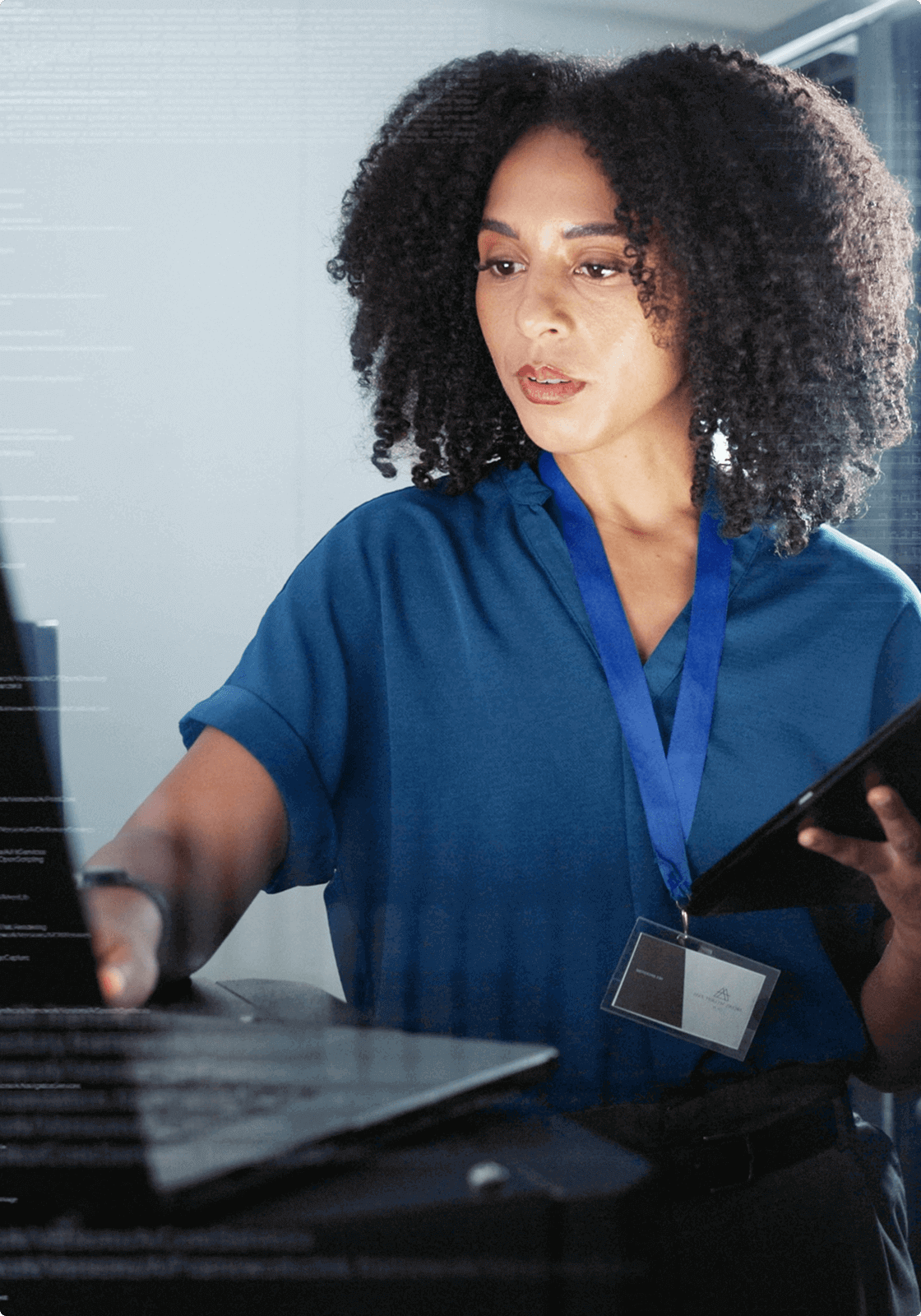 A woman with a tablet works on a laptop to repair a computer issue, representing the consistent maintenance of servers done by UsenetServer.