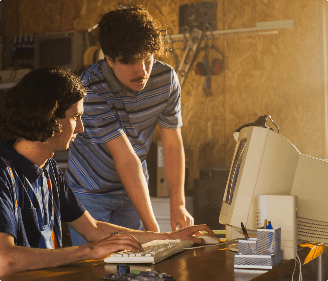 Two men work on a retro computer, showing Usenet’s early history and how it was developed.